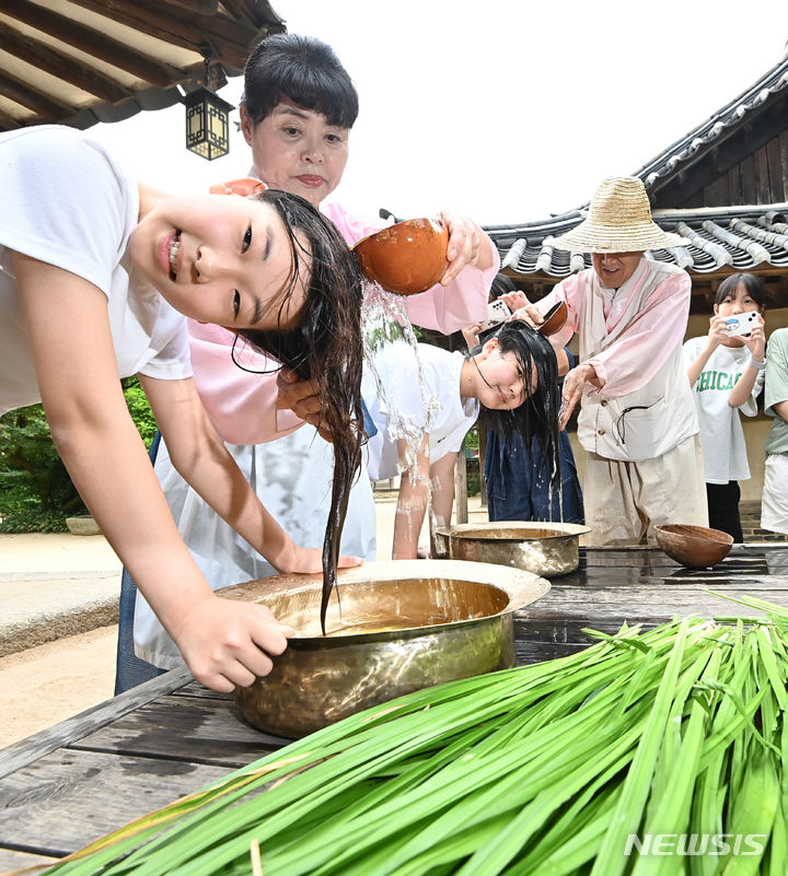 [용인=뉴시스] 김종택 기자 = 단오를 이틀 앞둔 20일 경기도 용인시 한국민속촌에서 학생들이 창포물에 머리를 감고 있다. 2023.06.20. jtk@newsis.com