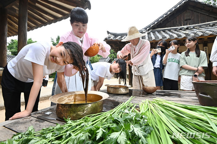 [용인=뉴시스] 김종택 기자 = 단오를 이틀 앞둔 20일 경기도 용인시 한국민속촌에서 학생들이 창포물에 머리를 감고 있다. 2023.06.20. jtk@newsis.com