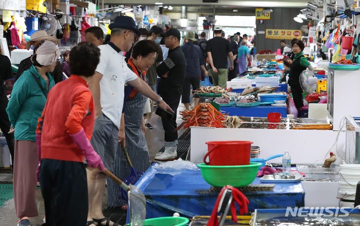 [강릉=뉴시스] 이영환 기자 = 22일 오후 강원 강릉시 주문진 좌판풍물시장을 찾은 관광객들이 수산물을 살펴보고 있다. 2023.06.22. 20hwan@newsis.com