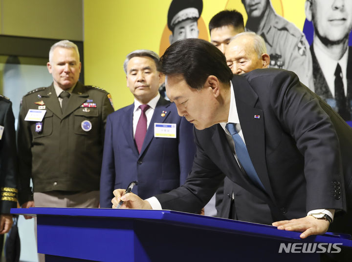 [서울=뉴시스] 전신 기자 = 윤석열 대통령이 25일 서울 종로구 대한민국역사박물관에서 열린 한미동맹 70주년 특별전을 찾아 '영웅을 기억하는 나라: 한미 참전용사 10대 영웅 전시' 코너 앞에서 방명록을 작성하고 있다. 2023.06.25. photo1006@newsis.com