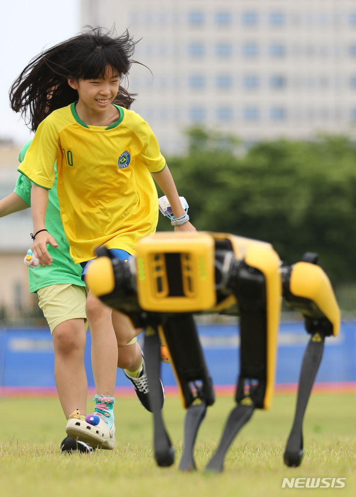 [서울=뉴시스] 황준선 기자 = 25일 오후 서울 용산구 용산어린이정원에서 열린 '로봇 그리고 인간: 로봇과 놀자' 행사를 찾은 어린이들이 사족보행 로봇과 뛰어놀고 있다. 2023.06.25. hwang@newsis.com