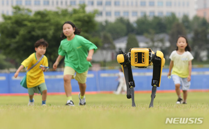 [서울=뉴시스] 황준선 기자 = 25일 오후 서울 용산구 용산어린이정원에서 열린 '로봇 그리고 인간: 로봇과 놀자' 행사를 찾은 어린이들이 사족보행 로봇과 뛰어놀고 있다. 2023.06.25. hwang@newsis.com