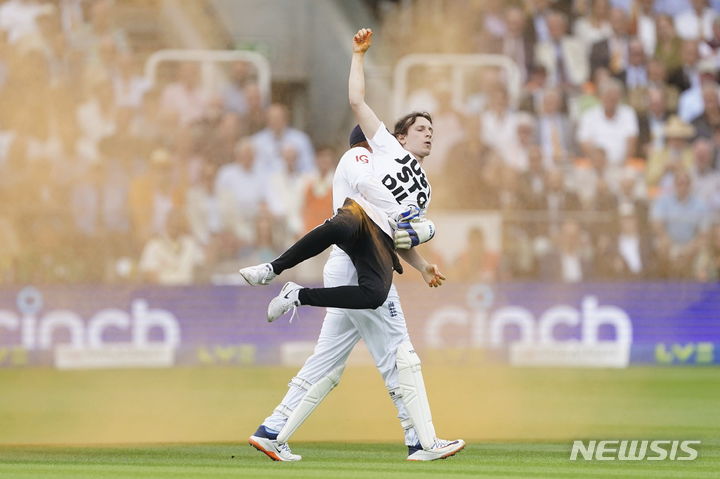 [런던=AP/뉴시스] 당구, 럭비 등 여러 스포츠 경기장에 난입해 오렌지색 페인트 가루를 뿌리며 시위를 한 영국 환경운동단체 저스트스탑오일이 지난 28일(현지시간) 영국 로드크리켓그라운드에서 열린 잉글랜드 대 호주 경기에서도 같은 시위를 벌였다고 미국 CNN은 전했다. 사진은 잉글랜드 조니 베어스토 선수에게 들려 나가는 한&nbsp; 환경운동가. 2023.07.03.