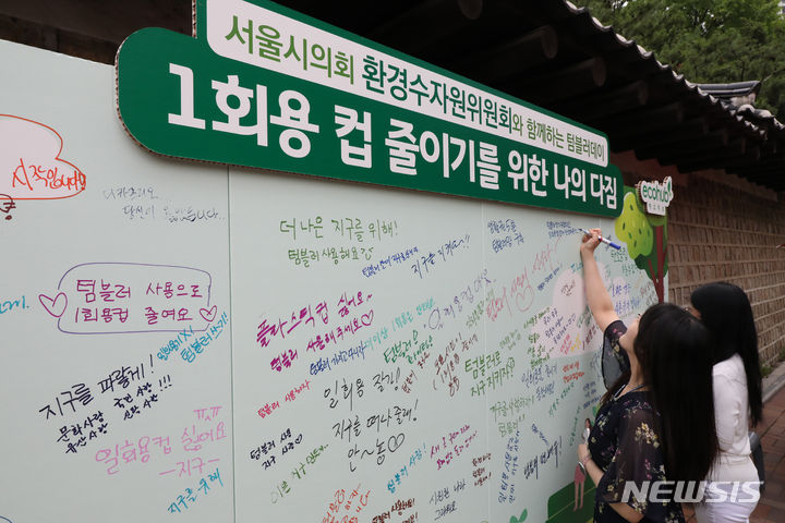 [서울=뉴시스] 김금보 기자 = 28일 오후 서울 중구 정동길 분수대 일대에서 열린 텀블러데이 행사에서 시민들이 1회용 컵 줄이기를 위한 다짐 글귀를 적고 있다. 2023.06.28. kgb@newsis.com