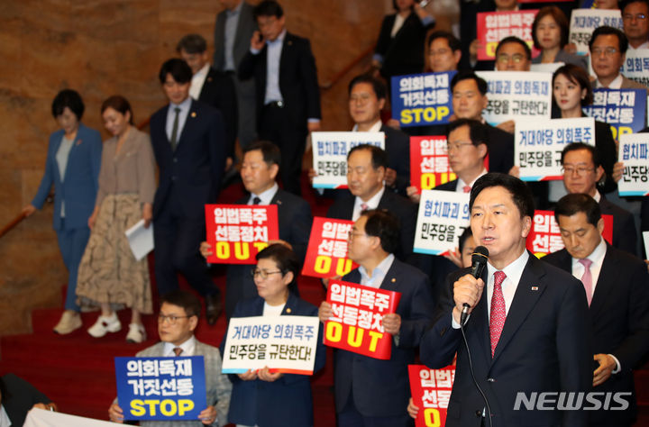 [서울=뉴시스] 고범준 기자 = 김기현 국민의힘 대표가 30일 오후 서울 여의도 국회 로텐더홀에서 열린 '입법폭주 의회독재 민주당 규탄 대회'에서 발언을 하고 있는 가운데 민주당 의원들이 그 옆을 지나가고 있다. 2023.06.30. bjko@newsis.com