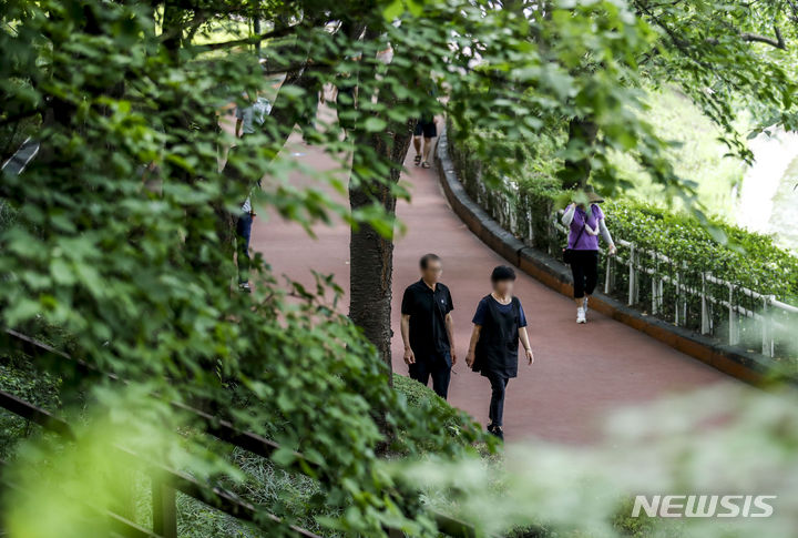 [서울=뉴시스] 정병혁 기자 = 더운 날씨가 이어진 3일 서울 송파구 석촌호수를 찾은 시민들이 나무 그늘 아래에서 이동하고 있다. 2023.07.03. jhope@newsis.com