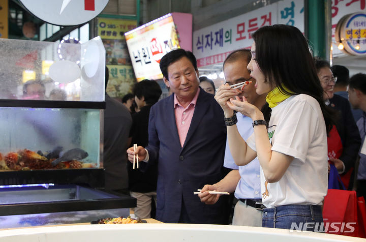 [강릉=뉴시스] 홍효식 기자 = 윤석열 대통령 부인 김건희 여사가 3일 오후 강원도 강릉 중앙·성남시장을 방문해 오징어회를 시식하고 있다. 2023.07.03. yesphoto@newsis.com