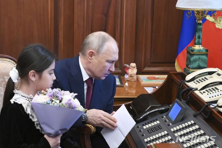 [모스크바=AP/뉴시스] 블라디미르 푸틴 러시아 대통령이 4일(현지시각) 모스크바 크렘린궁에서 다게스탄 공화국 데르벤트에서 온 8세 소녀 라이사트 아키포바와 함께 안톤 실루아노프 재무장관에게 전화하고 있다. 푸틴 대통령은 지난달 28일 데르벤트를 방문했을 때 자신을 만나지 못해 눈물 흘리는 라이사트의 사진을 뒤늦게 보고 라이사트 가족을 크렘린궁에 초대했다. 푸틴 대통령은 실루아노프 장관에게 전화해&nbsp; 라이사트를 바꿔주었고 라이사트는 다게스탄에 대한 예산 지원을 요청해 50억 루블(약 713억 원)의 예산 지원을 약속받았다. 2023.07.05.
