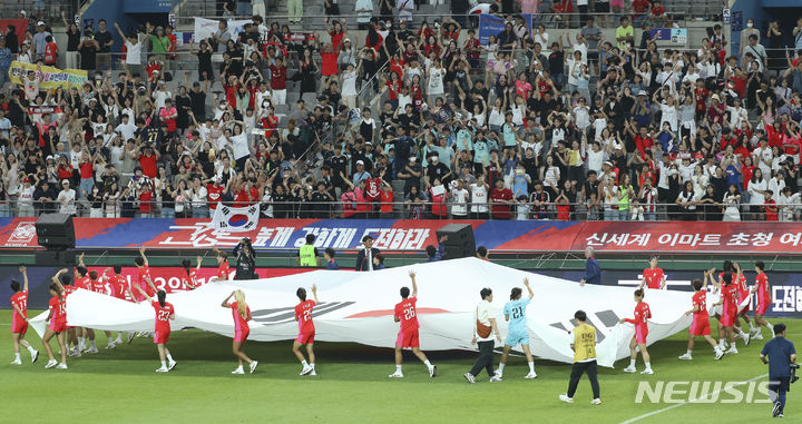 [서울=뉴시스] 최진석 기자 = 8일 서울 마포구 상암동 서울월드컵경기장에서 열린 대한민국 여자축구대표팀 2023 FIFA 호주/뉴질랜드 여자 월드컵 출정식에서 선수들이 대형 태극기를 들고 관중들에게 인사를 하고 있다. 2023.07.08. myjs@newsis.com