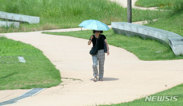 [전주=뉴시스] 김얼 기자 = 지난달 10일 전북 전주시 덕진구 세병공원에서 한 시민이 우산으로 햇빛을 피하며 산책을 하고 있다. 2023.07.10. pmkeul@nwsis.com