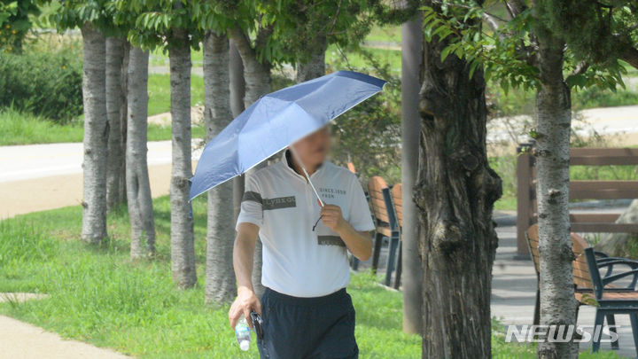 [전주=뉴시스] 김얼 기자 = 10일 전북 전주시 덕진구 세병공원에서 한 시민이 우산으로 햇빛을 피하며 산책을 하고 있다. 2023.07.10. pmkeul@nwsis.com