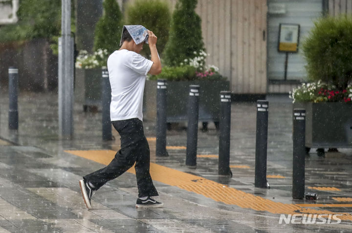 [서울=뉴시스] 정병혁 기자 = 장맛비가 내린 11일 오전 서울 중구 세종대로 인근에서 한 시민이 신문으로 머리를 가린 채 뛰어가고 있다. 2023.07.11. jhope@newsis.com