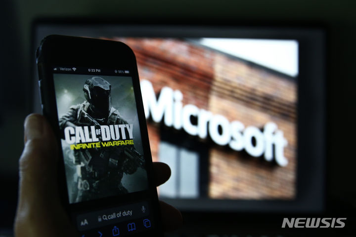 [캘리포니아=AP/뉴시스] 지난 16일(현지 시간) 미국 CNBC는 마이크로소프트가 액티비전블리자드 인수 후 게임 타이틀 콜 오브 듀티를 소니의 게임콘솔 플레이스테이션에서도 앞으로 10년간 이용할 수 있는 계약을 체결했다고 보도했다. 사진은 마이크로소프트 로고 사진 근처에 스마트폰으로 표시한 콜 오브 듀티 사진의 모습. 2023.07.17.