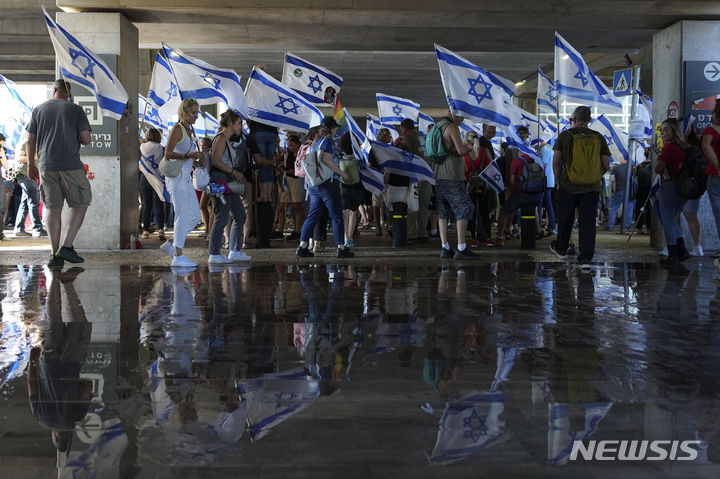 [텔아비브=AP/뉴시스] 7월11일 이스라엘 텔아비브 인근 벤구리온 국제공항에서 베냐민 네타냐후 총리의 사법개혁에 반대하는 시위대가 국기를 들고 시위하고 있다. 이 날 네타냐후 총리에 반대하는 역대 최대 규모의 시위와 집회가 이스라엘 전역에서 열렸다. 2023.07.17.