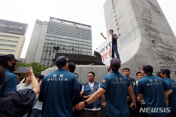 [서울=뉴시스] 조성봉 기자= 12일 오전 서울 종로구 광화문 이순신 동상 위에서 민주노총 조합원들이 ‘일본 후쿠시마 오염수 해양투기 반대’, ‘윤석열 대통령 퇴진’ 등 구호를 외치며 기습시위를 하고 있다. 경찰이 연행하려 하자 민주노총 조합원들이 스크럼을 짜고 구호를 외치고 있다. 2023.07.12. suncho21@newsis.com