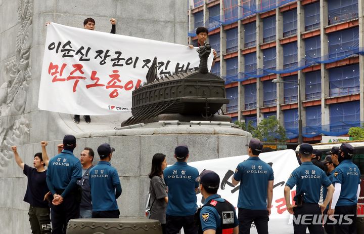 [서울=뉴시스] 조성봉 기자= 12일 오전 서울 종로구 광화문 이순신 동상 위에서 민주노총 조합원들이 ‘일본 후쿠시마 오염수 해양투기 반대’, ‘윤석열 대통령 퇴진’ 등 구호를 외치며 기습시위를 하고 있다. 경찰이 연행하려 하자 민주노총 조합원들이 스크럼을 짜고 구호를 외치고 있다. 2023.07.12. suncho21@newsis.com