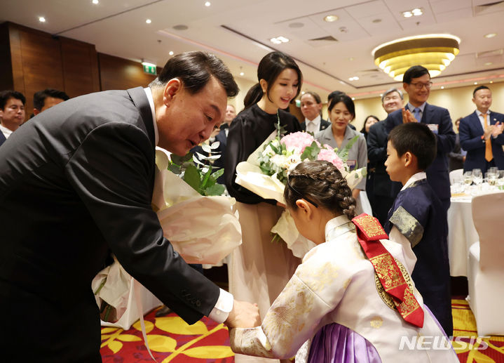 [바르샤바(폴란드)=뉴시스] 홍효식 기자 = 폴란드를 공식 방문한 윤석열 대통령과 김건희 여사가 12일(현지시간) 바르샤바 한 호텔에서 열린 동포간담회에 입장하며 화동으로부터 꽃다발을 받고 있다. 2023.07.13. yesphoto@newsis.com