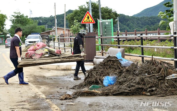 [괴산=뉴시스] 강신욱 기자 = 충북 괴산군 공무원들이 17일 괴산댐에서 방류된 물이 넘치면서 침수 피해를 본 하류지역 주택을 찾아 목재를 운반하는 등 복구 작업을 벌이고 있다. 2023.07.17. ksw64@newsis.com