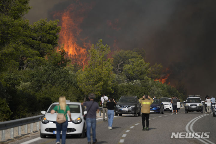 [아테네=AP/뉴시스] 그리스 중부 아테네 인근 국도에서 11월 15일 관광버스 한 대가 전복돼 타고있던 13명이 다쳤다. 사진은 그리스 산불로 전국 도로가 위험해지면서 2023년 7월 18일 아기아 소티라 마을 주민들이 도로 근방의 불타는 수목을 바라보고 있는 장면. 2025.11.16. 