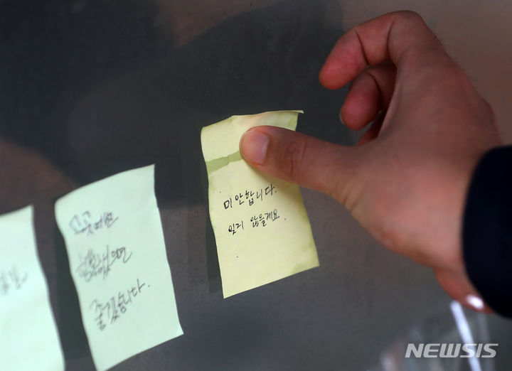 [서울=뉴시스] 김명년 기자 = 23일 오전 서울 관악구 신림역 '묻지마 흉기난동' 사건 현장에서 한 시민이 추모메시지를 붙이고 있다. 2023.07.23. kmn@newsis.com