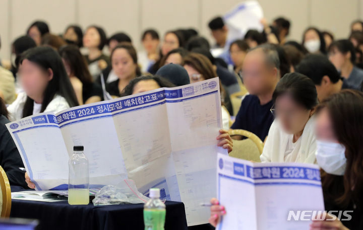 [서울=뉴시스] 김금보 기자 = 23일 서울 광진구 세종대학교 광개토관 컨벤션홀에서 열린 '종로학원 2024 수시정시 합격 예상 점수 공개 및 수험생 지원전략 설명회'에서 학부모들이 정시모집 배치참고표를 살펴보고 있다. 2023.07.23. kgb@newsis.com