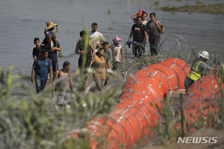 [리오 그란데( 미 텍사스주)=AP/뉴시스] 멕시코에서 리오 그란데 강을 건너 미국으로 오려던 이민들이 지난 7월 11일 텍사스주가 이글 패스 시의 강물위에 거대한 부표국경선을 설치하는 장소에 도착해 이를 구경하고 있다. 2023.07.25. 