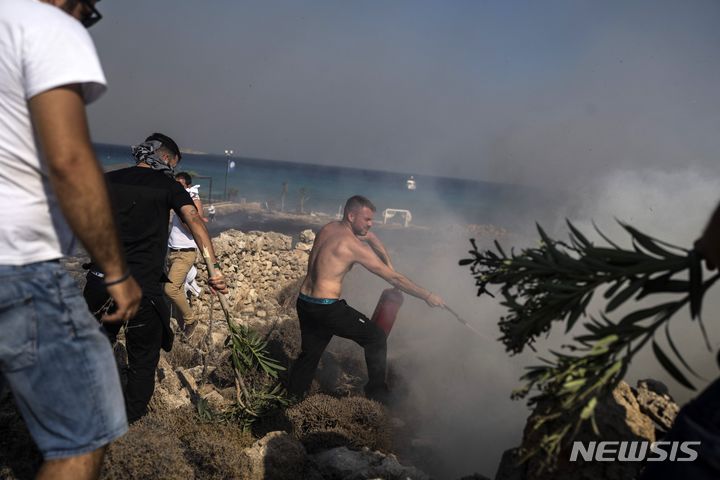 [로도스=AP/뉴시스] 24일(현지시각) 그리스 로도스섬의 해안 휴양지 린도스 리조트 인근에서 한 남성이 산불을 끄고 있다. 로도스섬의 산불이 1주일간 계속되면서 방어선이 무너지고 강한 바람과 연이은 폭염으로 또 다른 3곳에서도 화재가 발생해 더 많은 사람에게 대피령이 내려졌다. 2023.07.25.