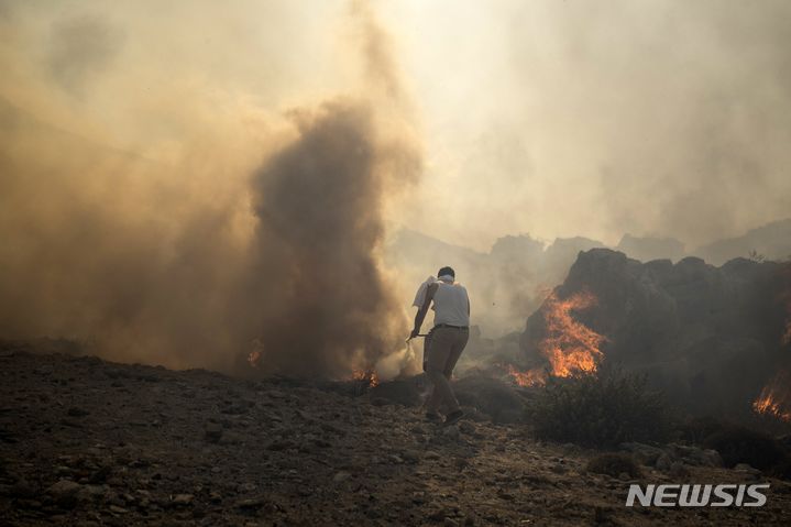 [로도스=AP/뉴시스] 24일(현지시각) 그리스 로도스섬의 해안 휴양지 린도스 리조트 인근에서 한 남성이 산불을 끄기 위해 애쓰고 있다. 로도스섬의 산불이 1주일간 계속되면서 방어선이 무너지고 강한 바람과 연이은 폭염으로 또 다른 3곳에서도 화재가 발생해 더 많은 사람에게 대피령이 내려졌다. 2023.07.25.