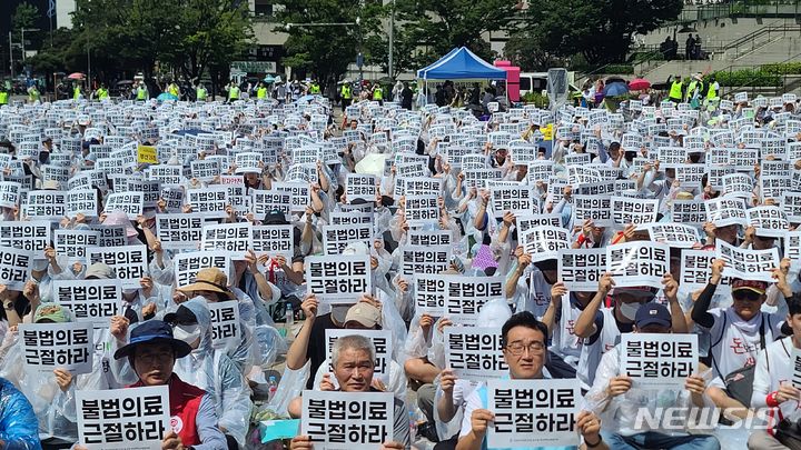 [부산=뉴시스] 권태완 기자 = 25일 오후 부산 동구 부산역 광장에서 보건의료노조 부산대병원지부가 총파업 13일차 출정식을 진행하고 있다. 출정식에 참여한 노조원들은 '불법의료 근절하라'라고 적힌 피켓을 들고 구호를 외치고 있다. 2023.07.25. kwon97@newsis.com