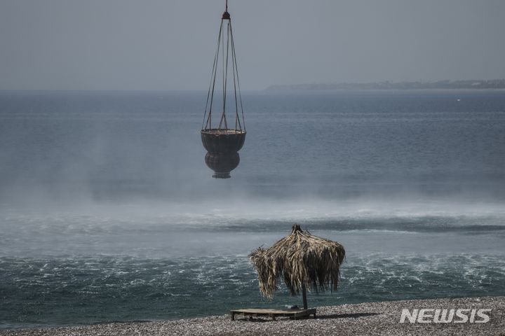 [로도스=AP/뉴시스] 27일(현지시간) 그리스 로도스 섬에서 헬리콥터가 산불 진화를 위해 물을 채우고 있다. 2023.07.28.