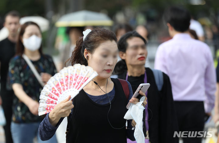 [서울=뉴시스] 황준선 기자 = 27일 오전 서울 종로구 세종대로 사거리에서 한 시민이 부채로 더위를 식히며 이동하고 있다. 2023.07.27. hwang@newsis.com