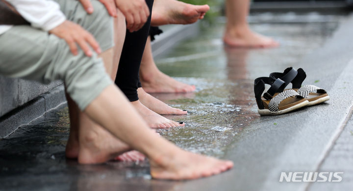 [서울=뉴시스] 김명년 기자 = 전국에 폭염 특보가 발효된 지난 7월29일 오후 서울 종로구 광화문광장에서 시민들이 신발을 벗고 물에 발을 담구고 있다. 2023.07.29. kmn@newsis.com