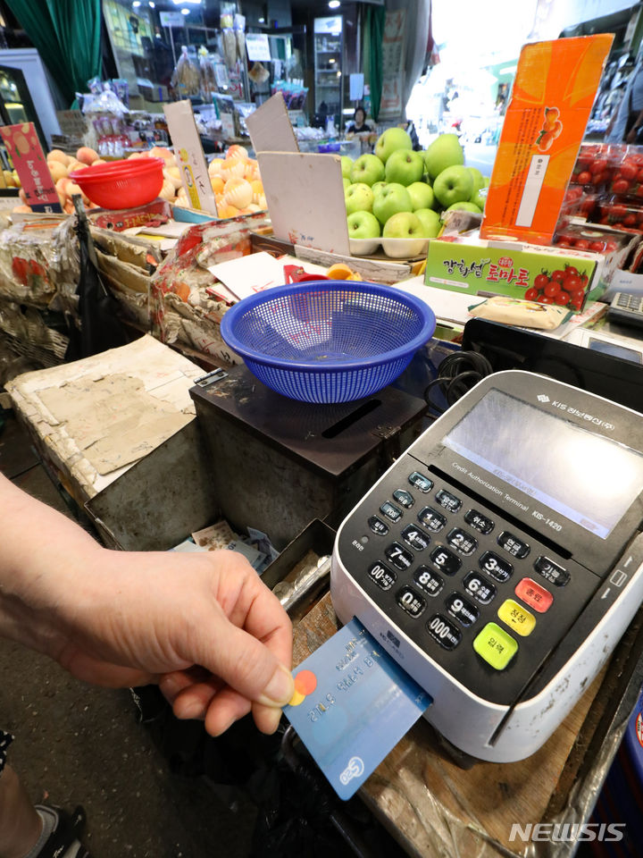 [서울=뉴시스] 황준선 기자 = 31일 오전 서울 마포구 망원시장의 한 점포에서 점주가 신용카드로 물건을 결제하고 있다. 2023.07.31. hwang@newsis.com