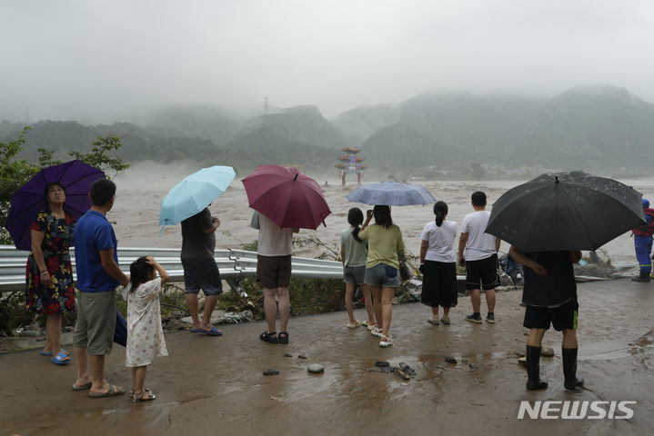 [베이징=AP/뉴시스] 1일 중국 베이징 외곽의 먀오펑산 지역 주민들이 홍수로 침수된 전통 패루를 바라보고 있다. 태풍 독수리의 영향으로 베이징에 폭우가 쏟아져 11명이 숨지고 약 30명이 실종된 것으로 나타났다. 2023.08.01.