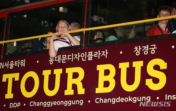 [서울=뉴시스] 황준선 기자 = 2023 새만금 세계 스카우트 잼버리에서 조기 퇴영한 영국 스카우트 대원이 6일 저녁 광화문 서울 시티투어버스에 탑승해 출발 전 하트를 그리고 있다. (공동취재사진) 2023.08.06. hwang@newsis.com