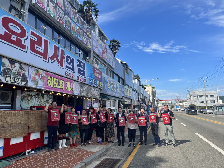 [통영=뉴시스] 신정철 기자= 경남 통영시는 한산대첩축제와 휴가철을 맞아 통영시를 대표하는 ‘착한 동백이 운동’에 참여한 업소에 대한 인증표지판을 부착했다. 천영기 통영시장이 도천상가 횟집거리 14개 업소에 대해 인증표지판을 부착하고 기념사진을 촬영하고 있다.(사진=통영시 제공).2023.08.08. photo@newsis.com *재판매 및 DB 금지