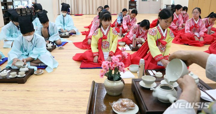 [부산=뉴시스] 하경민 기자 = '초등학생 여름방학 전통문화 체험교실'이 열린 7일 오전 부산 동래구 충렬사 안락서원 교육회관에서 초등학생들이 한복을 곱게 차려입고 다도 예절을 배우고 있다. 초등학생 40여 명이 참가한 이번 체험교실에서는 다도 및 서당 체험과 민요 배우기, 민속놀이 체험 등을 오는 11일까지 진행한다. 2023.08.07. yulnetphoto@newsis.com