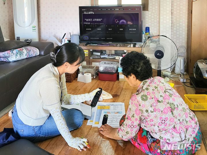 [진도=뉴시스] 진도군보건소 직원이 ‘지니 TV 케어’ 사용법을 노인에게 알려주고 있다.