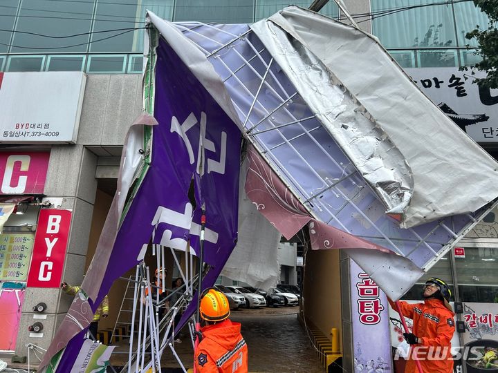 [화순=뉴시스] 김혜인 기자 = 10일 오전 전남 화순군 화순읍 한 건물 간판이 강풍에 떨어져 소방 당국이 전선에 걸린 간판을 제거하고 있다. 2023.08.10. (사진=전남도소방본부 제공) photo@newsis.com *재판매 및 DB 금지