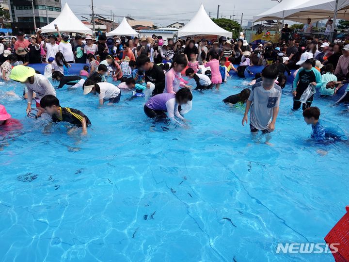 [제주=뉴시스] 오영재 기자 = 12일 오후 제주시 도두동 오래물광장에서 열린 제21회 도두오래물축제에서 어린이들이 맨손 미꾸라지 잡기 체험을 하고 있다. 2023.08.12. oyj4343@newsis.com