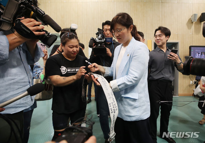 [진천=뉴시스] 고승민 기자 = 장미란 문화체육관광부 제2차관이 16일 충북 진천 국가대표 선수촌을 찾아 2022 항저우 하계아시아경기대회 개막을 앞두고 훈련에 매진하고 있는 역도 선수단을 찾아 후배에게 사인을 해주고 있다. 2023.08.16. kkssmm99@newsis.com