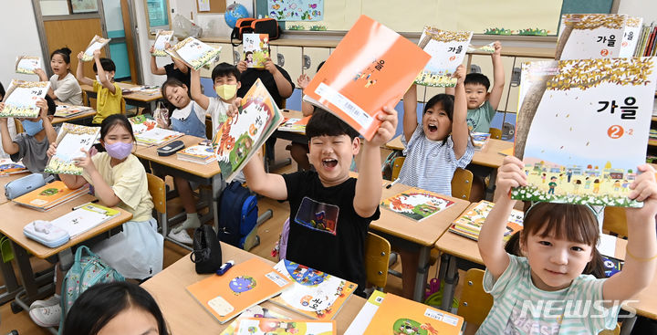 [수원=뉴시스] 김종택 기자 = 초등학교 개학이 시작된 16일 오전 경기도 수원시 영화초등학교 2학년1반 학생들이 새학기 교과서를 들어보이며 즐거워하고 있다. 2023.08.16. jtk@newsis.com