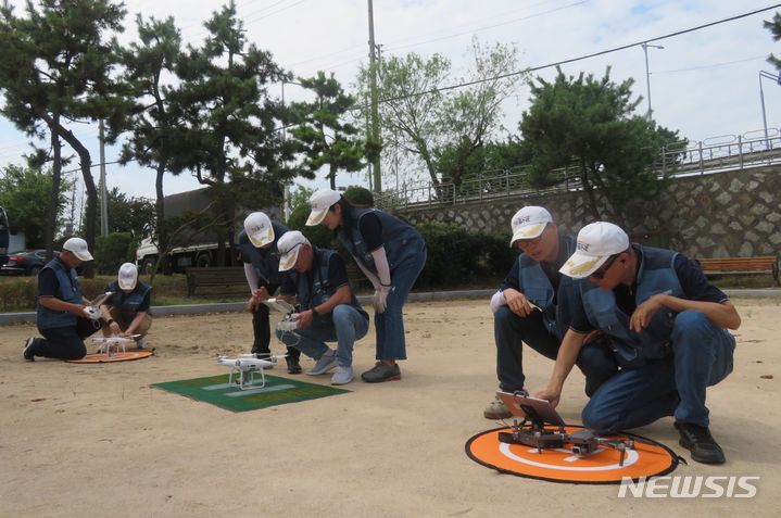 [부산=뉴시스] 이동민 기자 = 부산 강서구의 공터에서 동의대 드론봉사단 단원들이 조종기를 이용해 드론을 띄울 준비를 하고 있다. 2023.08.18. eastsky@newsis.com 