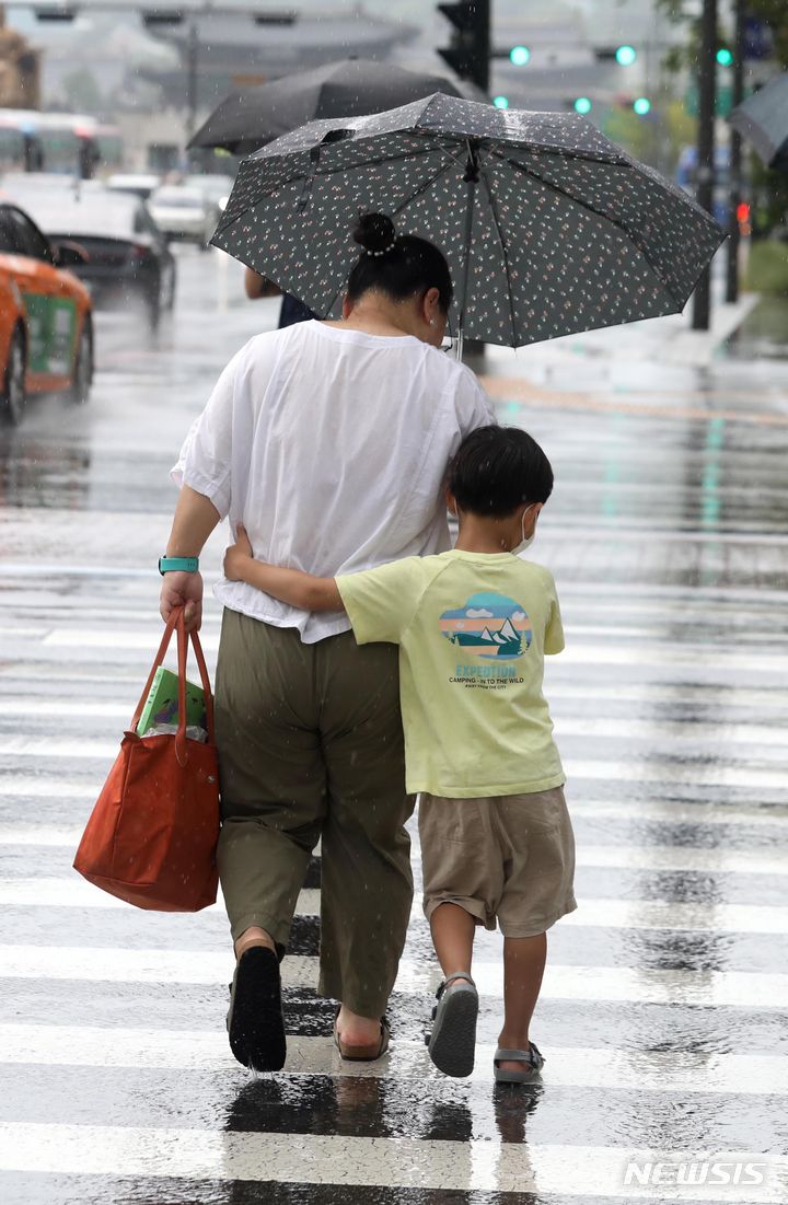 [서울=뉴시스] 조성봉 기자 = 비가 내린 오후 서울 종로구 광화문 네거리에서 한 아이가 엄마와 함께 우산을 쓰고 이동하고 있다. 2023.08.22. suncho21@newsis.com