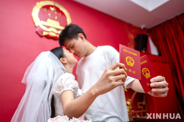 [후저우=신화/뉴시스]한 커플이 지난 8월22일 중국 동부 저장성 후저우에서 결혼증을 들고 사진을 찍기 위해 포즈를 취하고 있다. 2023.11.20.