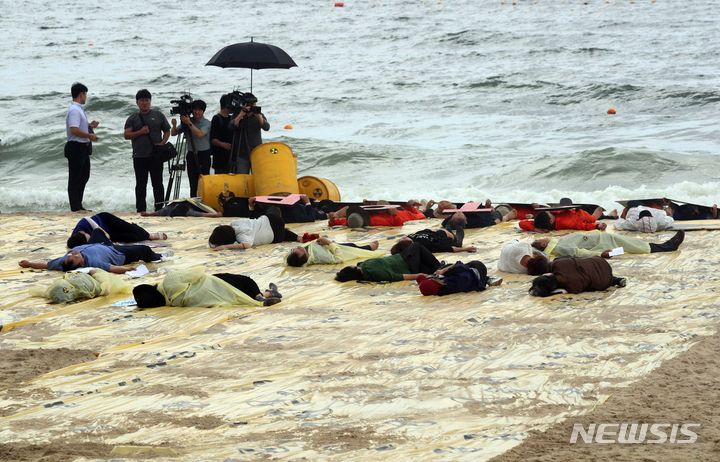 [부산=뉴시스] 하경민 기자 = 일본 후쿠시마 원전 오염수 해양 방류를 시작하는 24일 부산 해운대구 해운대해수욕장에서 환경운동연합 바다위원회 등 여러 환경·시민단체의 활동가들이 노란색 비닐 등으로 원전 오염수가 부산 앞바다에 밀려온 것을 표현하며 해양투기를 반대하는 캠페인을 펼치고 있다. 2023.08.24. yulnetphoto@newsis.com