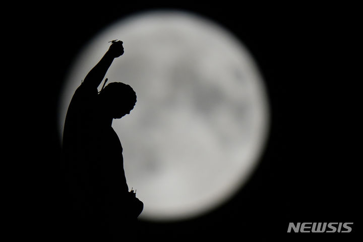[밀라노=AP/뉴시스] 30일(현지시각) 이탈리아 밀라노의 두오모 고딕 성당 첨탑 뒤로 '슈퍼 블루문'이 떠오르고 있다. 이번 보름달은 '슈퍼 블루문'으로 한달에 2번 뜨는 슈퍼문을 의미한다. 2023.08.31.