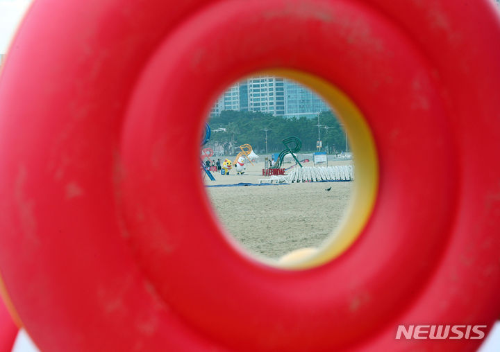 [부산=뉴시스] 하경민 기자 = 해운대·송정·광안리·다대포·송도·일광·임랑 등 부산 7개 해수욕장 폐장일인 31일 해운대해수욕장에서 튜브 구멍 사이로 상인들이 피서객에게 대여하던 비치파라솔 등 물놀이 용품을 치우는 모습이 보이고 있다. 2023.08.31. yulnetphoto@newsis.com