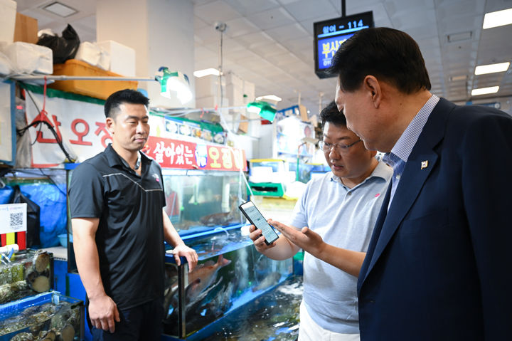 [서울=뉴시스] 윤석열 대통령이 31일 서울 동작구 노량진수산시장을 찾아 판매대에 QR코드를 스캔해 확인한 수산물 방사능 검사 결과를 보고 있다. (사진=대통령실 제공) 2023.08.31. photo@newsis.com *재판매 및 DB 금지
