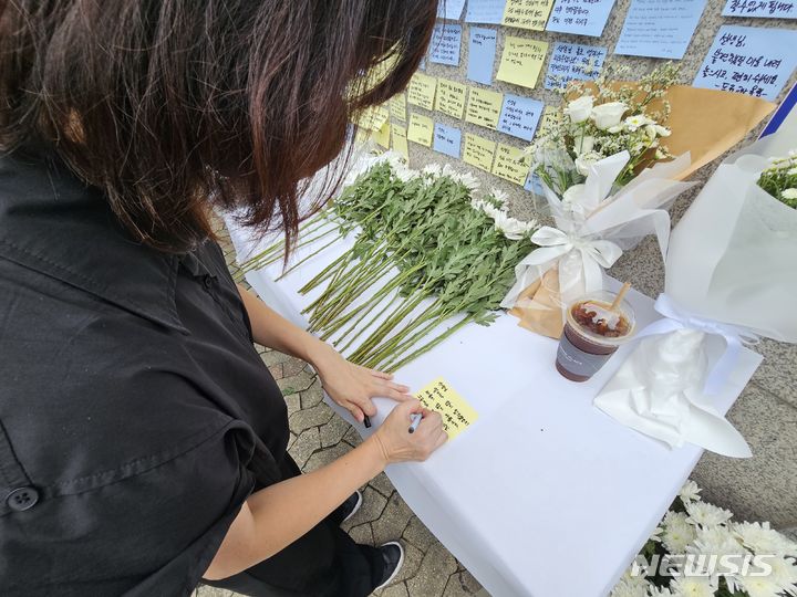 [용인=뉴시스] 양효원 기자 = 4일 오후 경기 용인시 기흥구 한 고등학교 앞에 전날 사망한 교사를 추모하는 조화가 놓여있는 가운데 경기지역 교사가 추모 글을 남기고 있다. 지난 3일 오전 10시 35분께 이 학교 체육교사 A(61)씨가 성남시 청계산 등산로에서 숨진 채 발견됐다. 2023.7.18. hyo@newsis.com